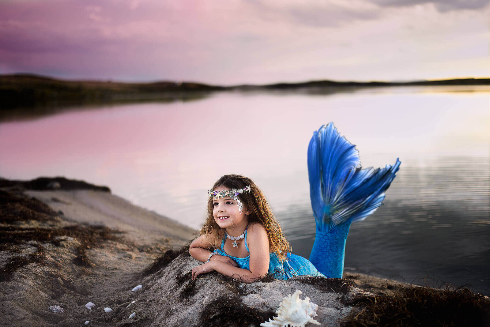 young child dressed as a mermaid with a blue tail laying on the beach near Pinedale Wyoming