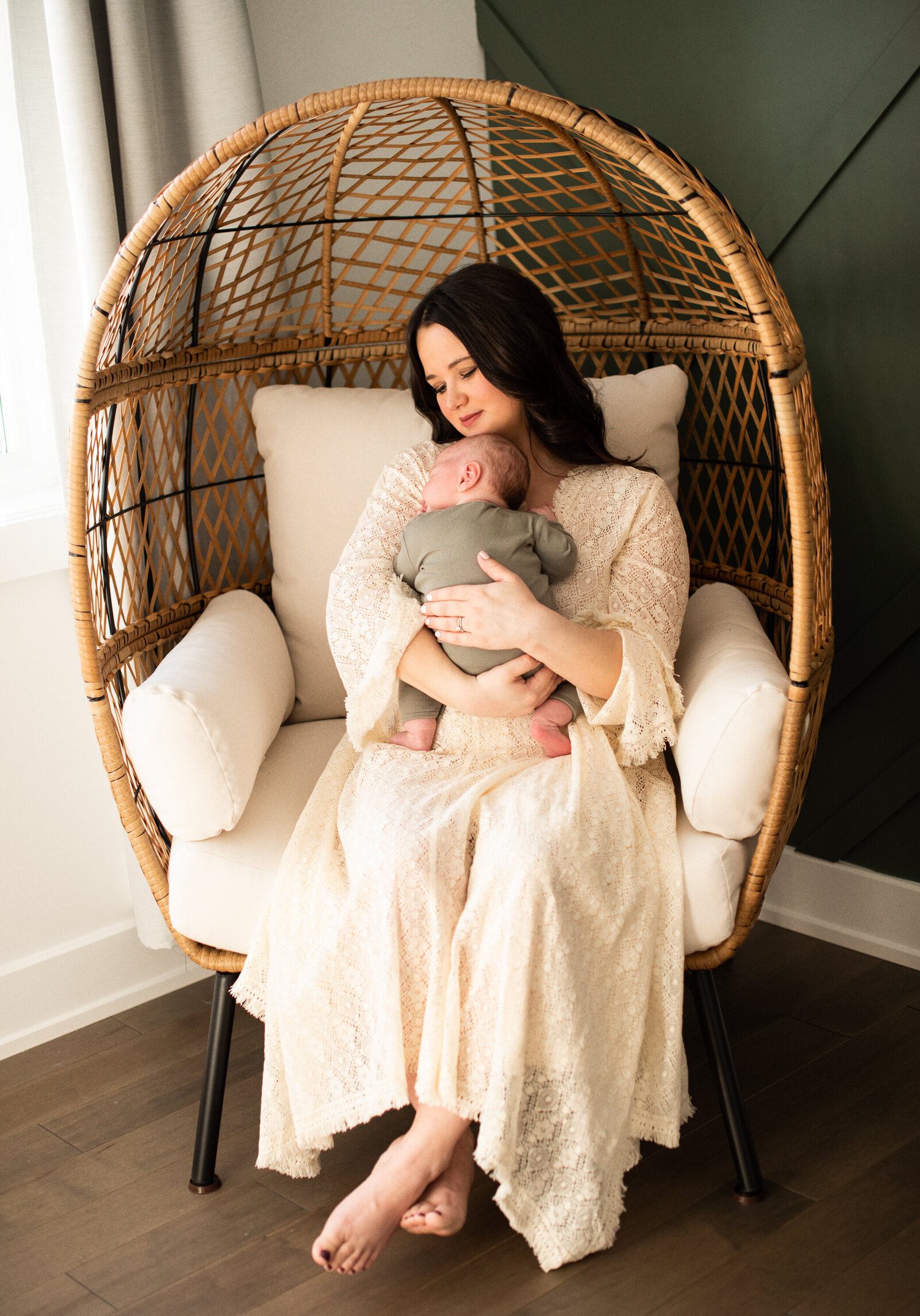 Mom holding her newborn baby in an egg chair.
