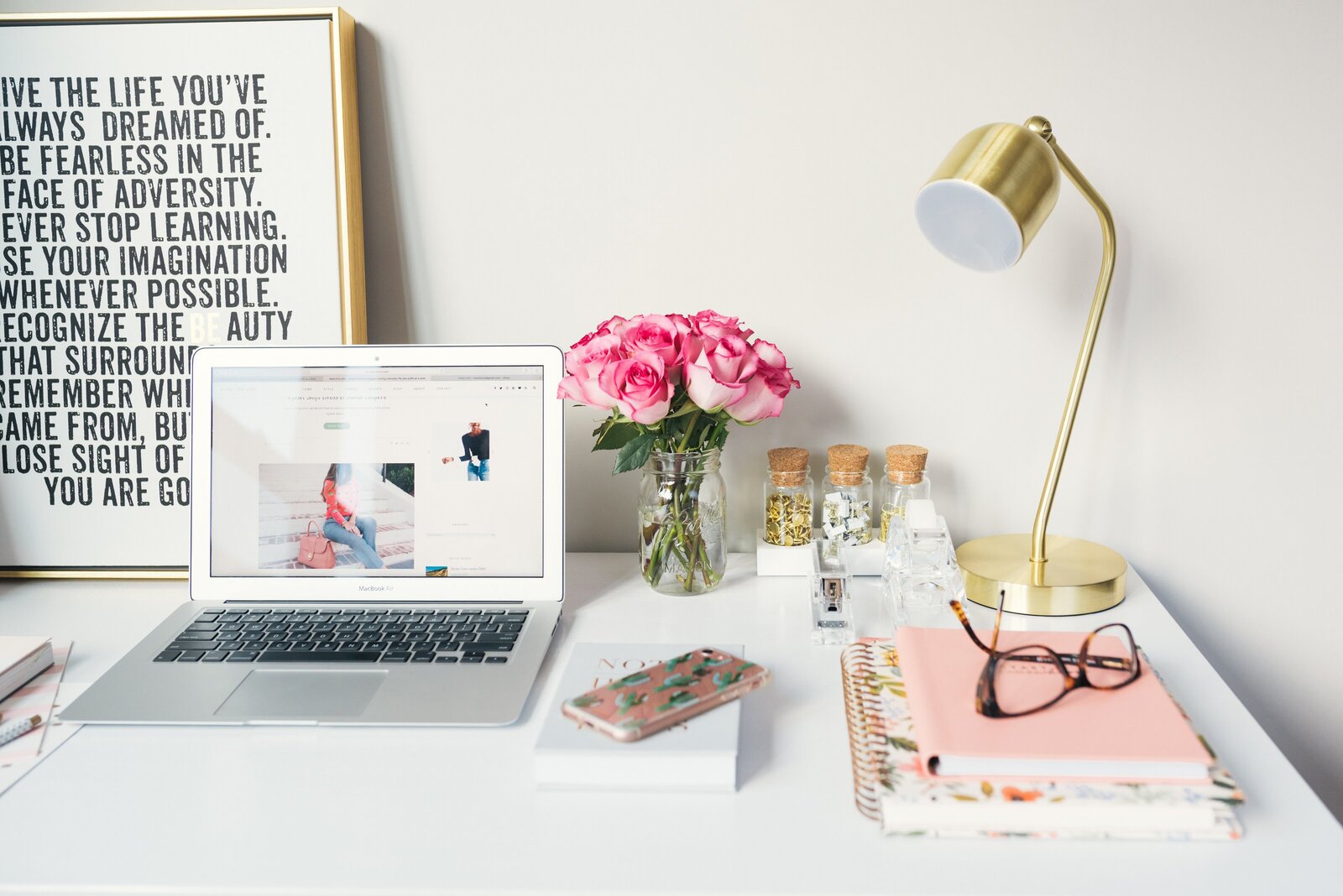 picture of a beautiful white desk with laptop, iphone and books and specs