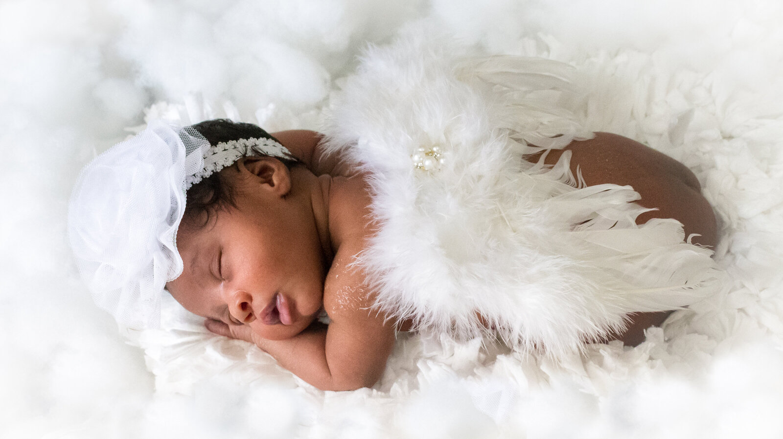 newborn sleeping in bed of cotton (clouds) with angel wings on back