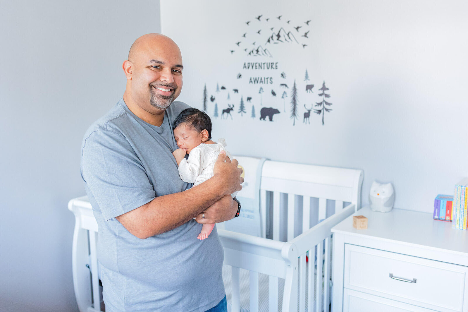 A dad holding his newborn son in the nursery.