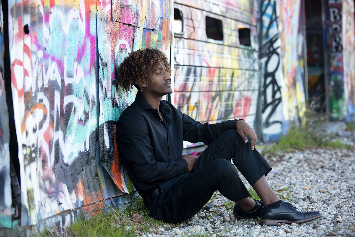 Frisco Senior boy sits in front of painted wall