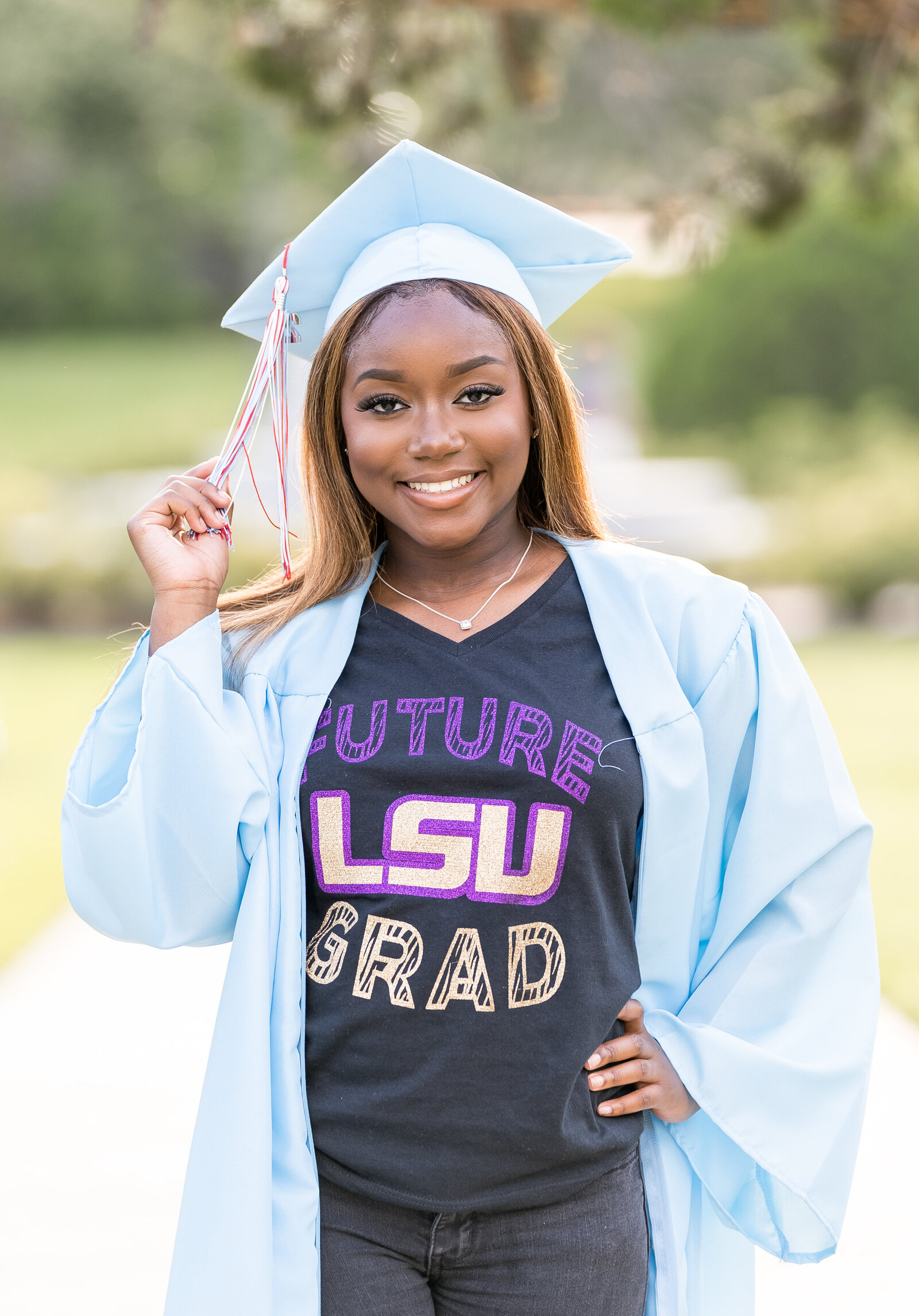 girl dressed in blue cap and gown with LSU tshirt holding the tassel