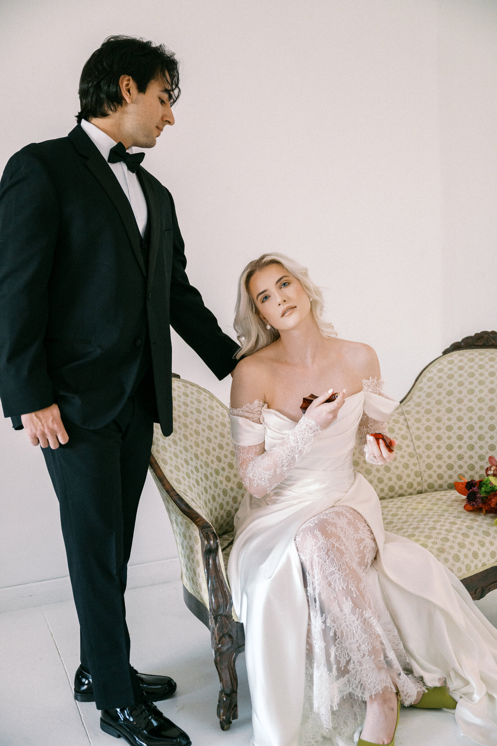 Modern bride and groom share an intimate moment — bride in satin gown with lace-trimmed veil holding a bold, tropical-inspired bouquet of orchids and anthuriums; groom in classic black tuxedo. Captured by Jordan Grover Photo, Missouri-based traveling wedding photographer specializing in artistic, editorial, and emotive wedding photography.