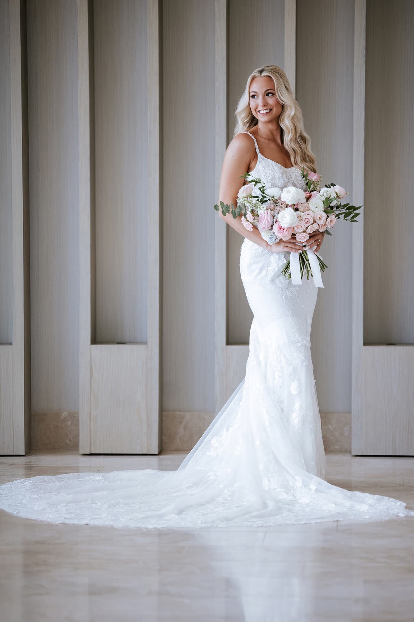 Elegant bridal portrait at Breathless Cancún Soul Resort & Spa in Cancún, Mexico, featuring a smiling bride in a fitted lace wedding gown holding a lush pastel bouquet, captured by destination wedding photographer Logrono & Co.
