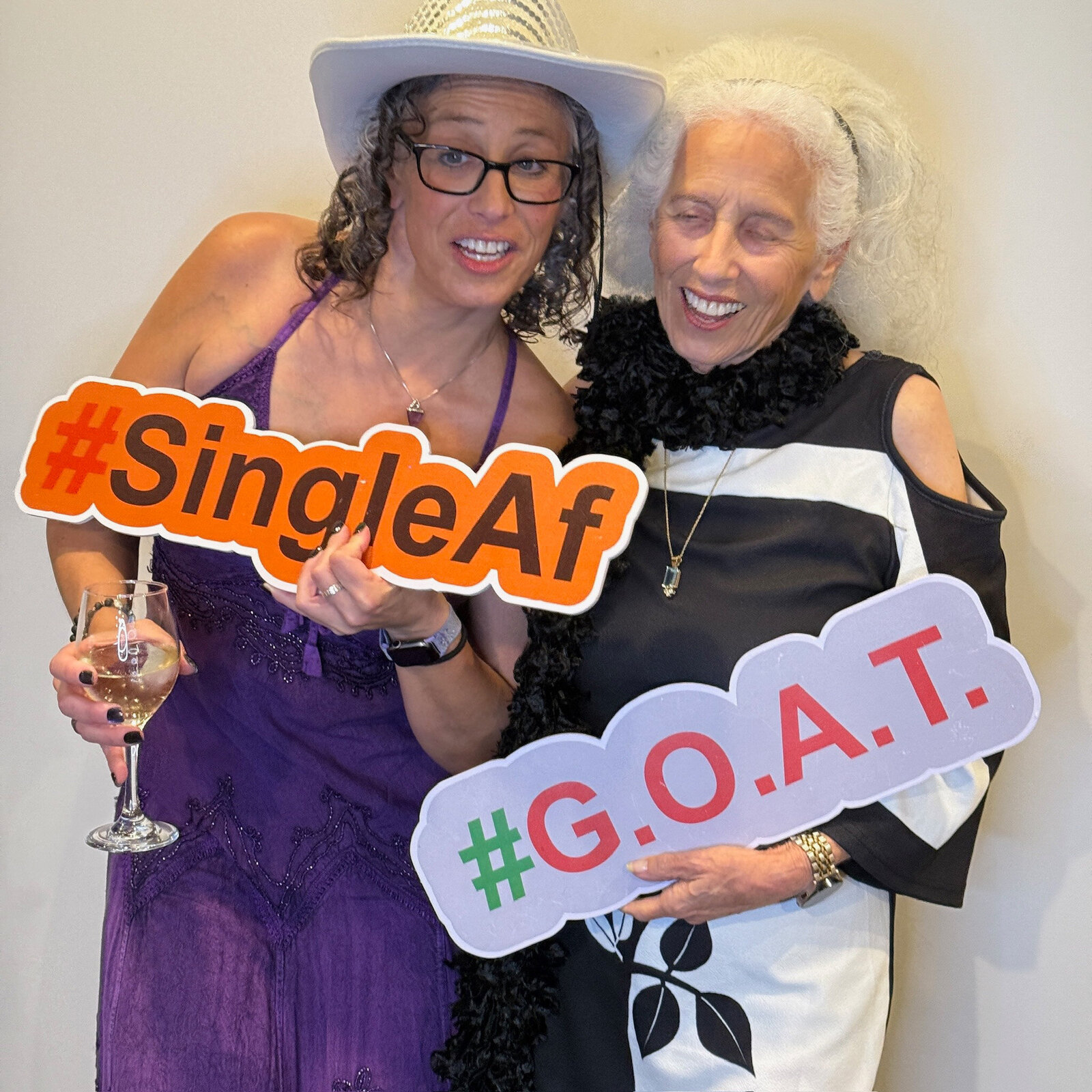 two women in photo booth holding a funny sign