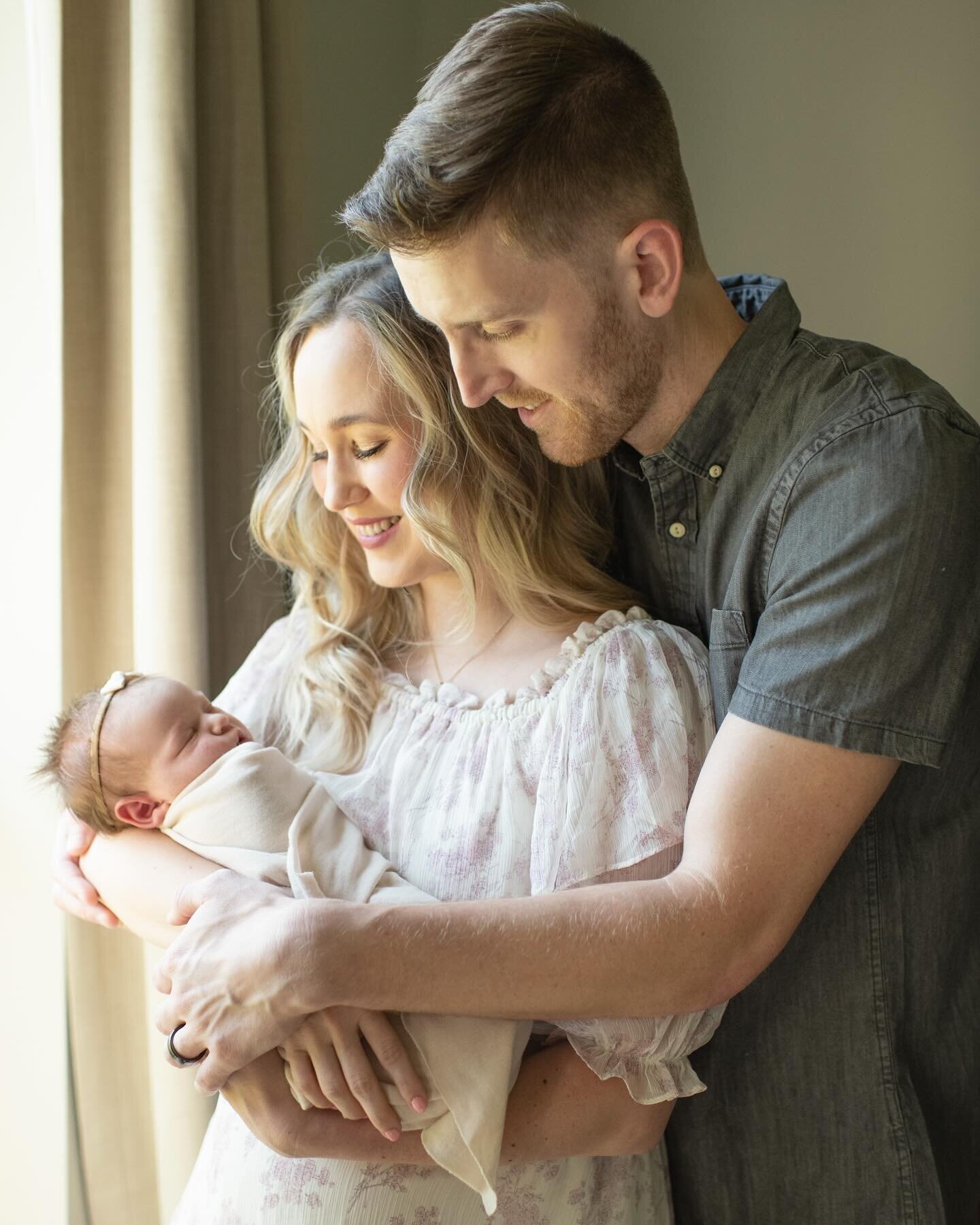 New parents hold their swaddled newborn close in a loving embrace. A heartfelt newborn session by Moments in Light Photography.