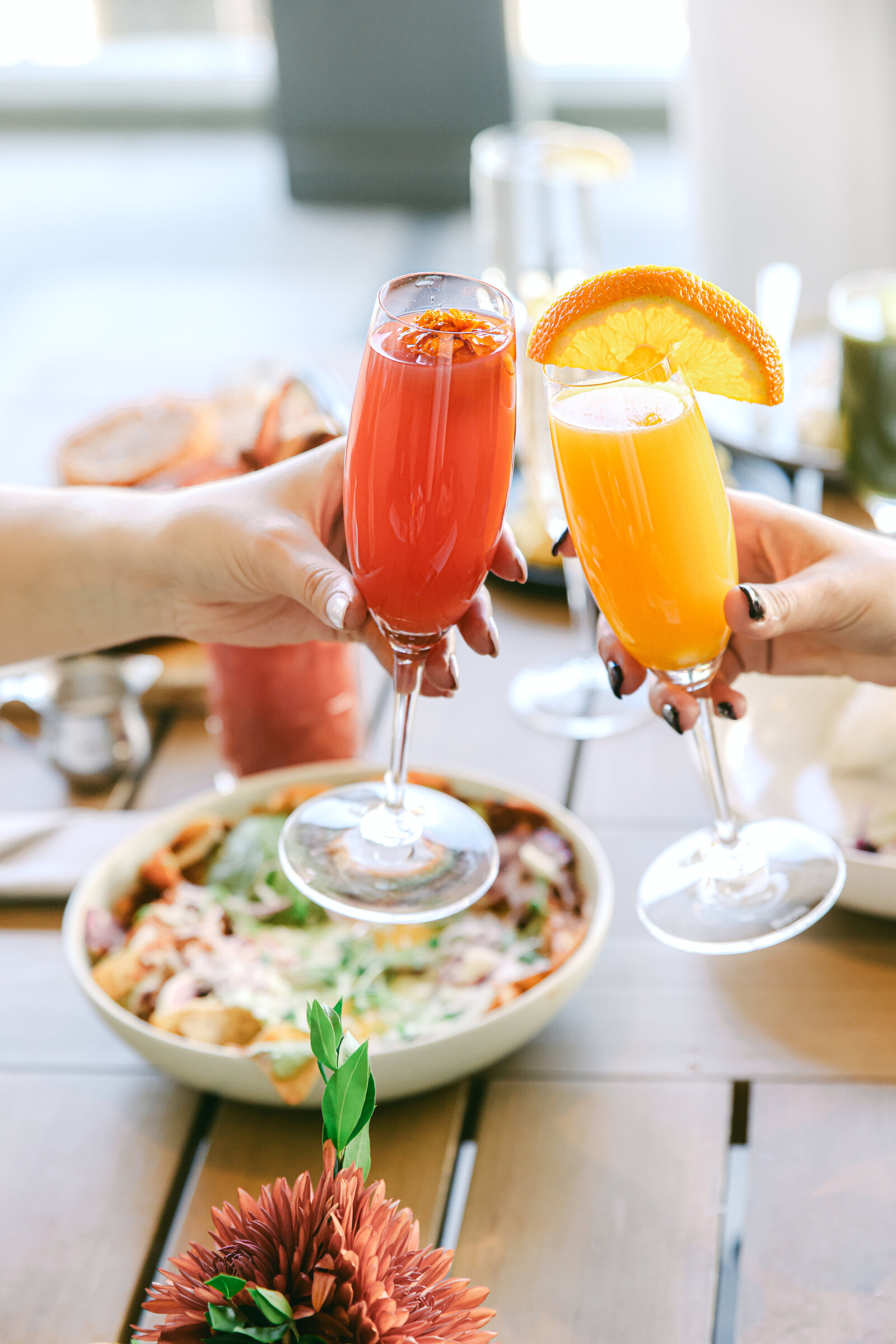 two girls cheersing their drinks at brunch by Chelsea Loren