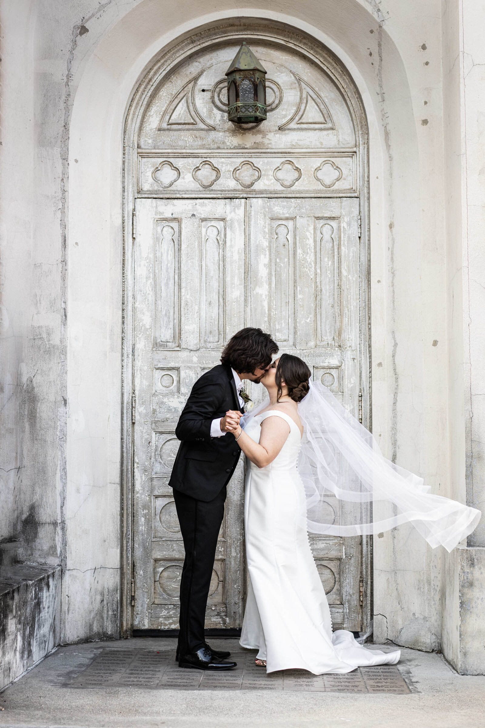 Bride and groom kiss in doorway of Hotel Peter and Paul in New Orleans