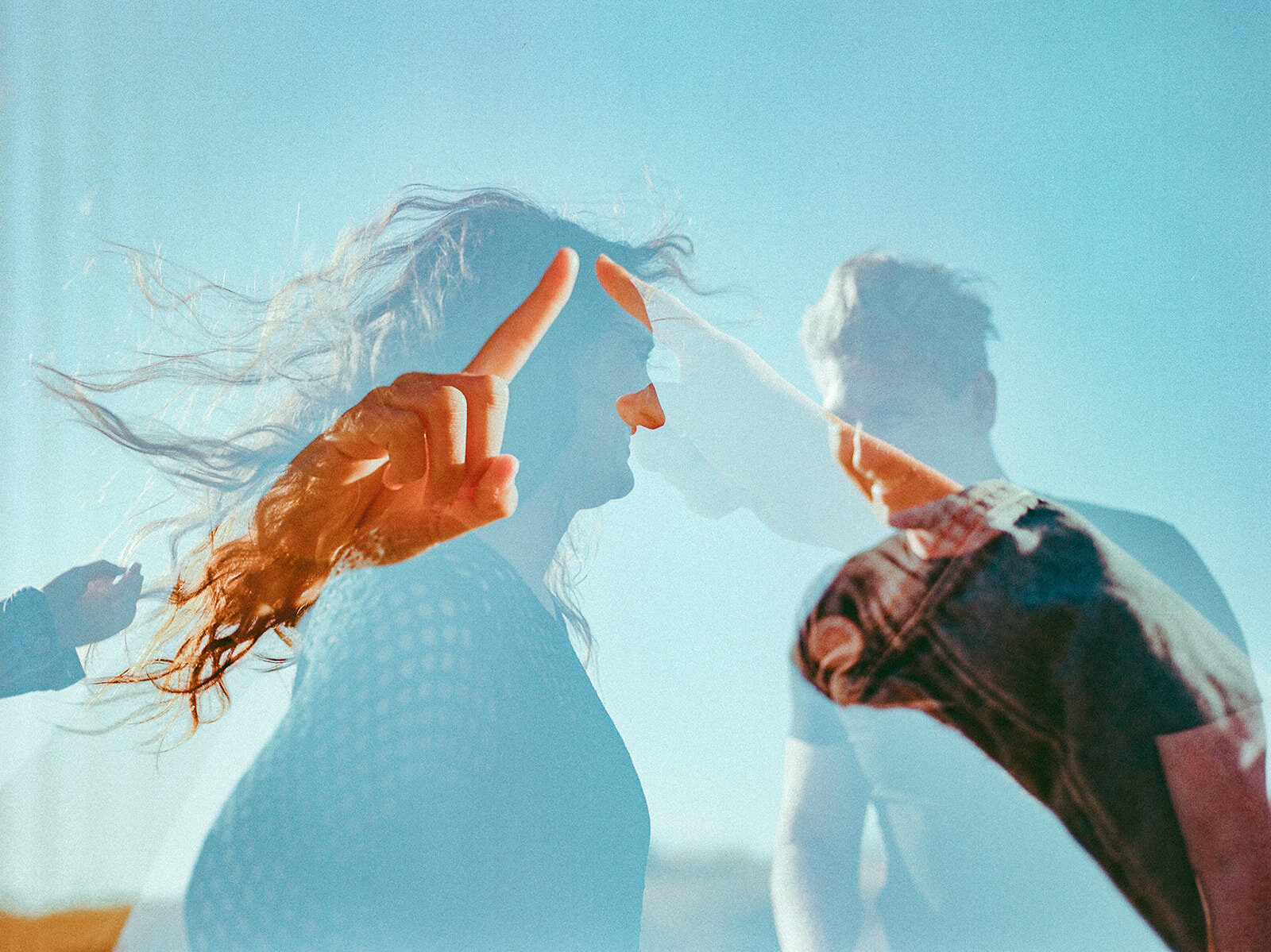 double exposure of husband and wife laughing with their daughters' fingers almost touching