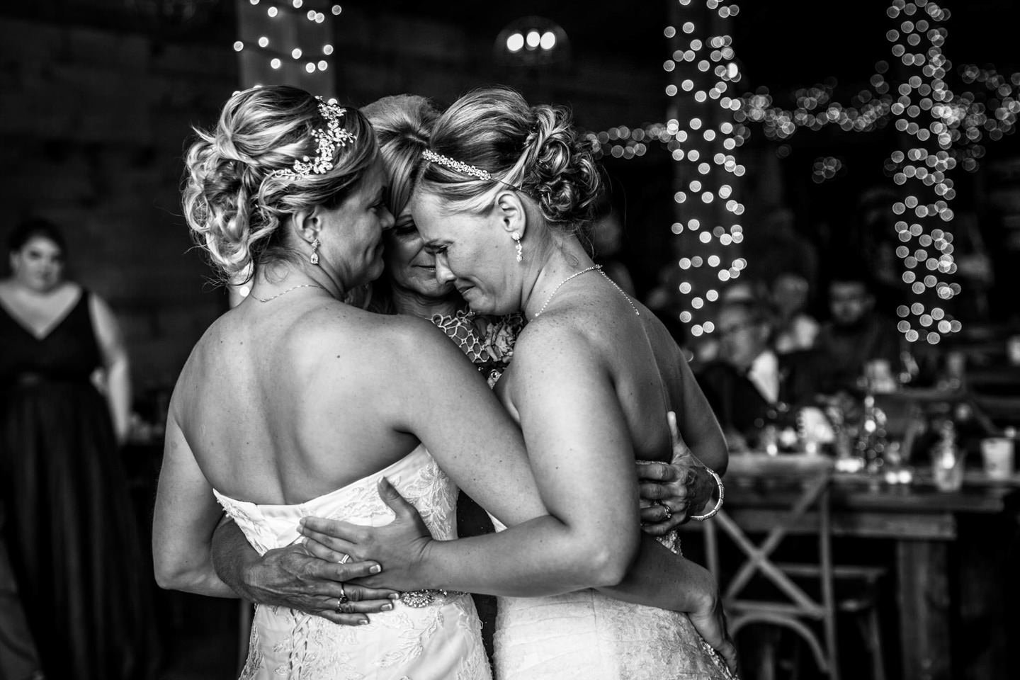 two brides dancing with mom during parent dance at Minneapolis barn wedding