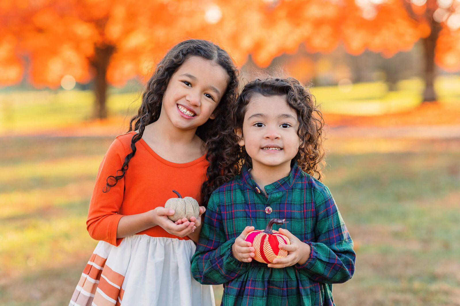 Two little girls holding pumpkins at a Northern VA park.