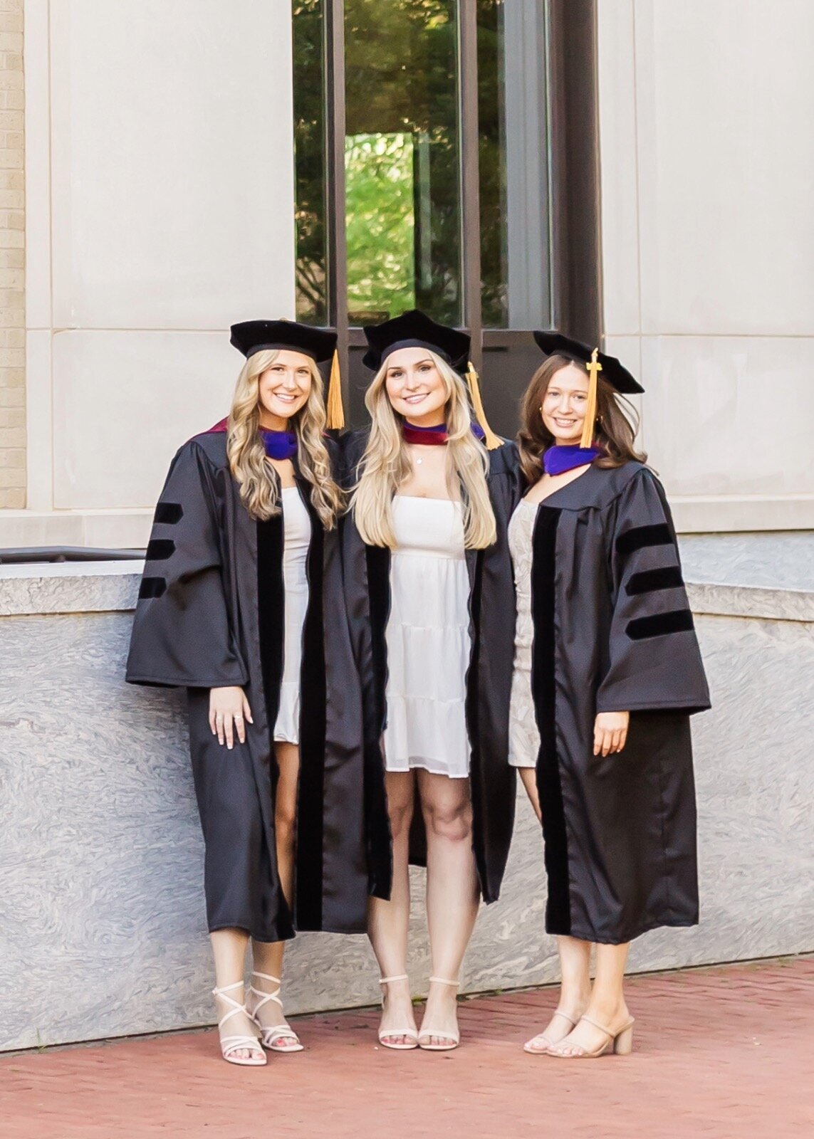 Three friends smiling in cap and gown