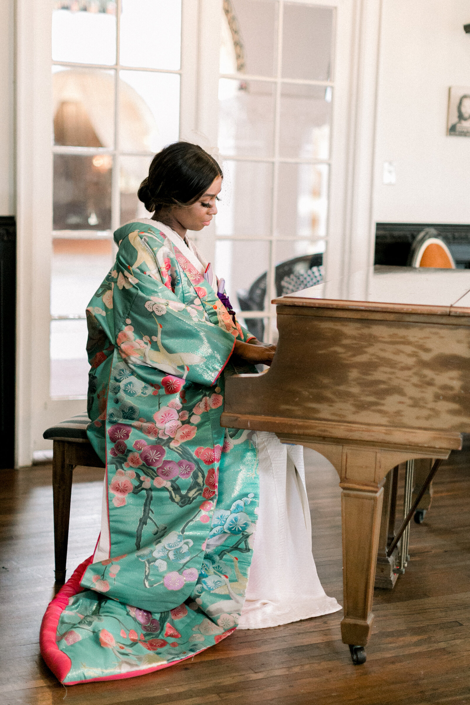 Bride in vibrant green floral uchikake wedding kimono seated gracefully at grand piano inside The Ebell Club Long Beach, kimono rental bridal portrait | ロングビーチ・エベルクラブのグランドピアノで華やかなグリーン色打掛を着た花嫁の着物レンタルウェディングポートレート
