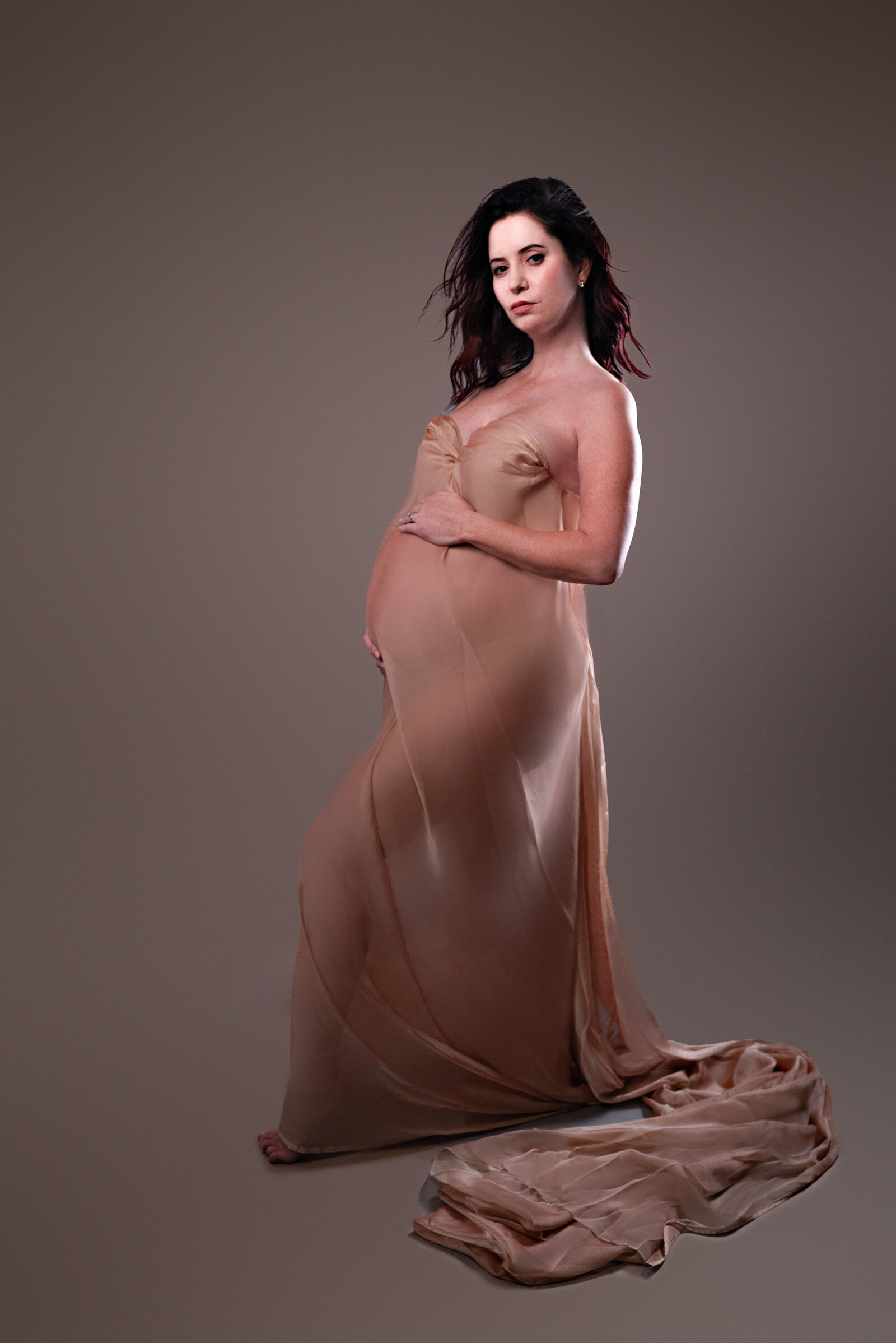 Pregnant woman wrapped in flowing fabric  and posing for the camera  in Huntsville Alabama