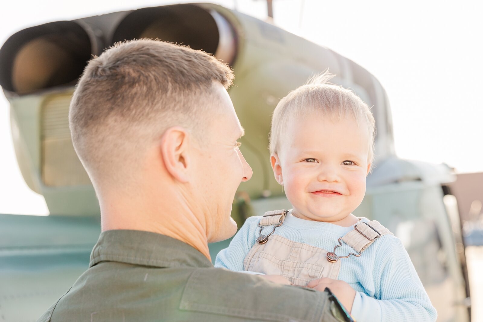 Little boy peaking over his pilot dad's shoulder