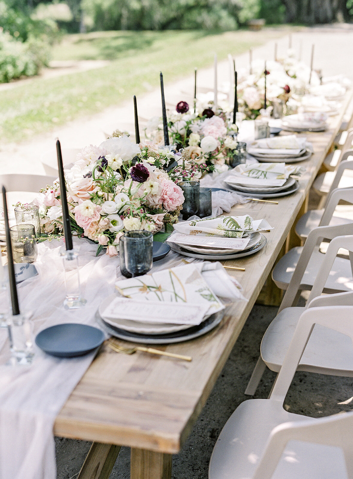 Ooh! Events designed outside reception table. White plates, gold flatware, black glassware and black and white candles and flowers going down the middle of the table and the full length of the king's table.  Photographed by wedding photographers in Charleston Amy Mulder Photography