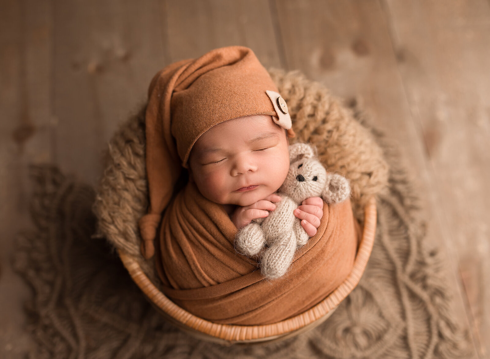 newborn baby boy holding bear