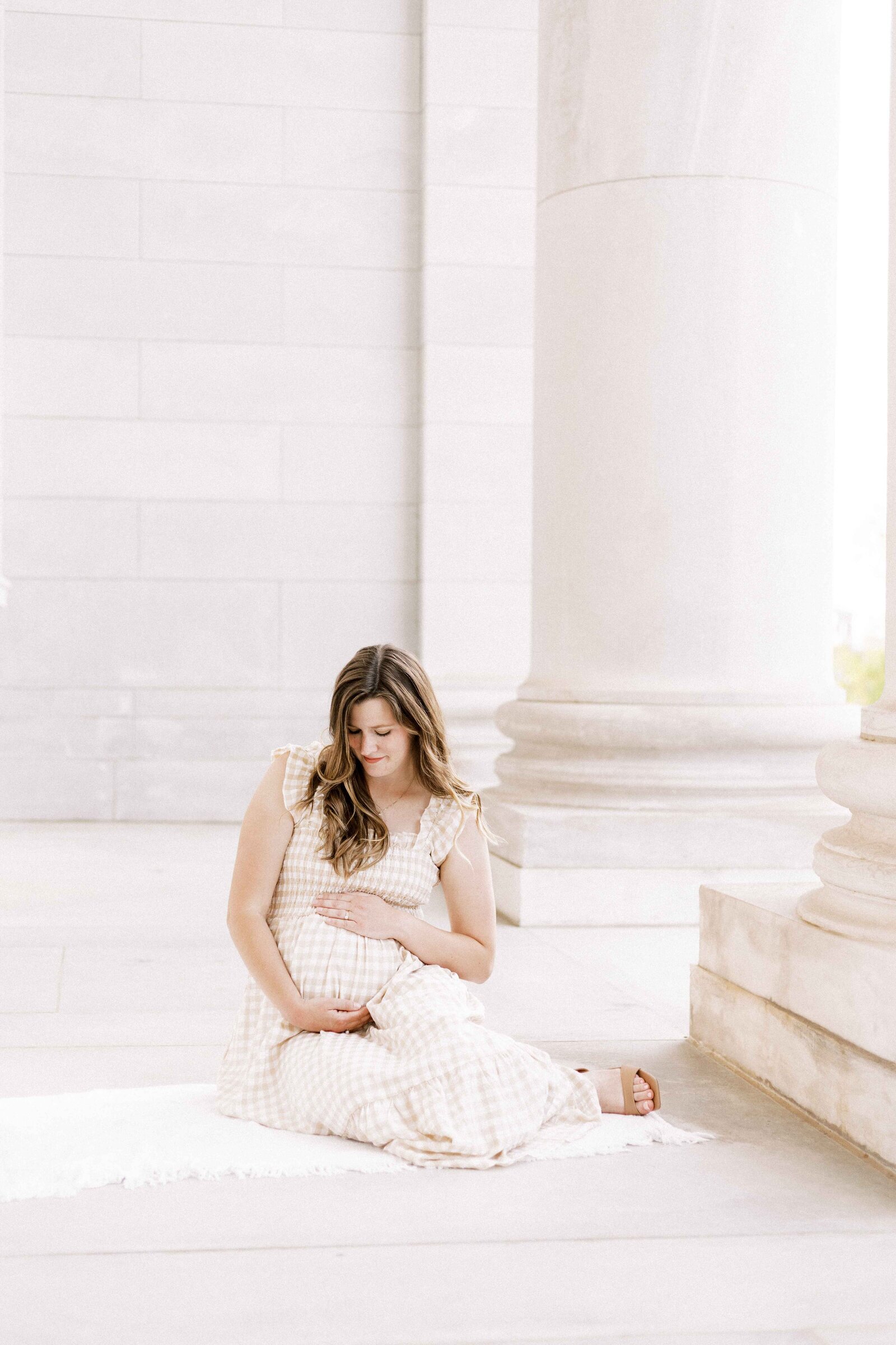 mom sitting down and cradling bump during maternity photos in peoria illinois 