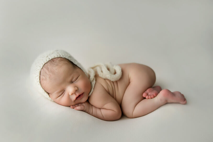 Posed newborn sleeps during his newborn photography session.