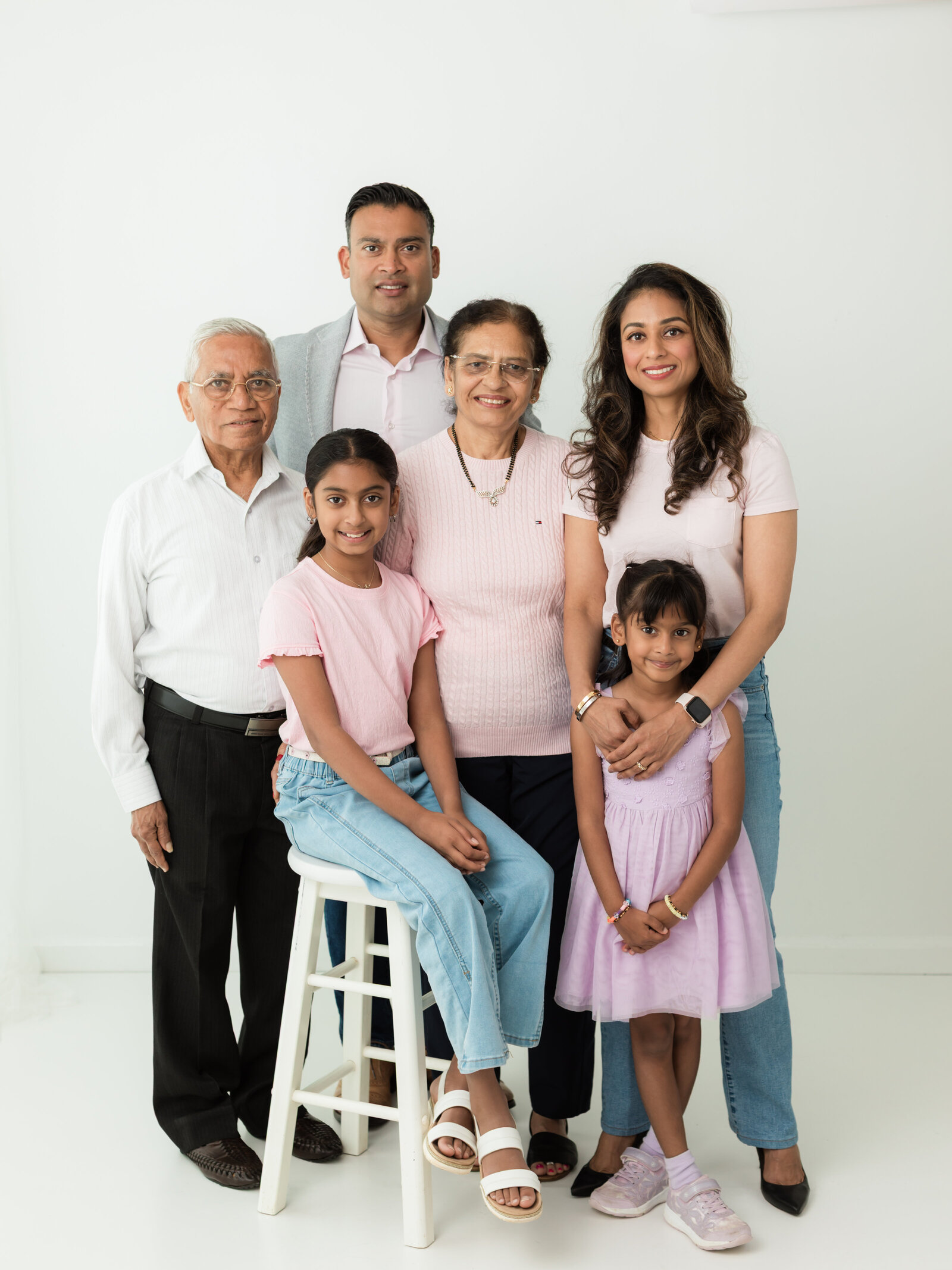 children, parents and grandparents posed for white studio portrait