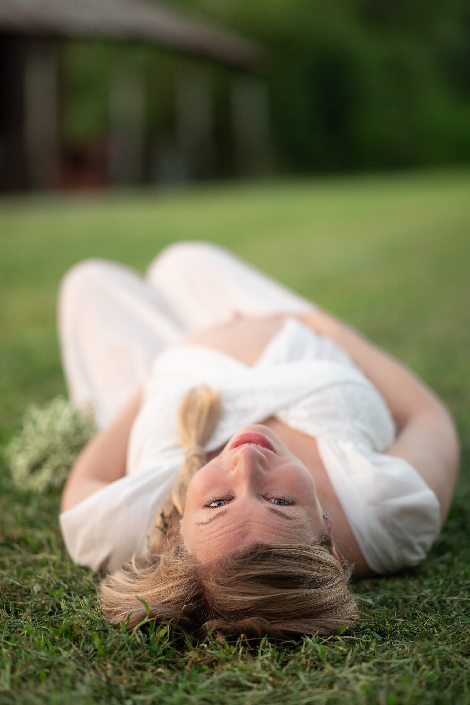 A  pregnant woman laying on the ground looking up at the camera for her Huntsville Alabama maternity pictures