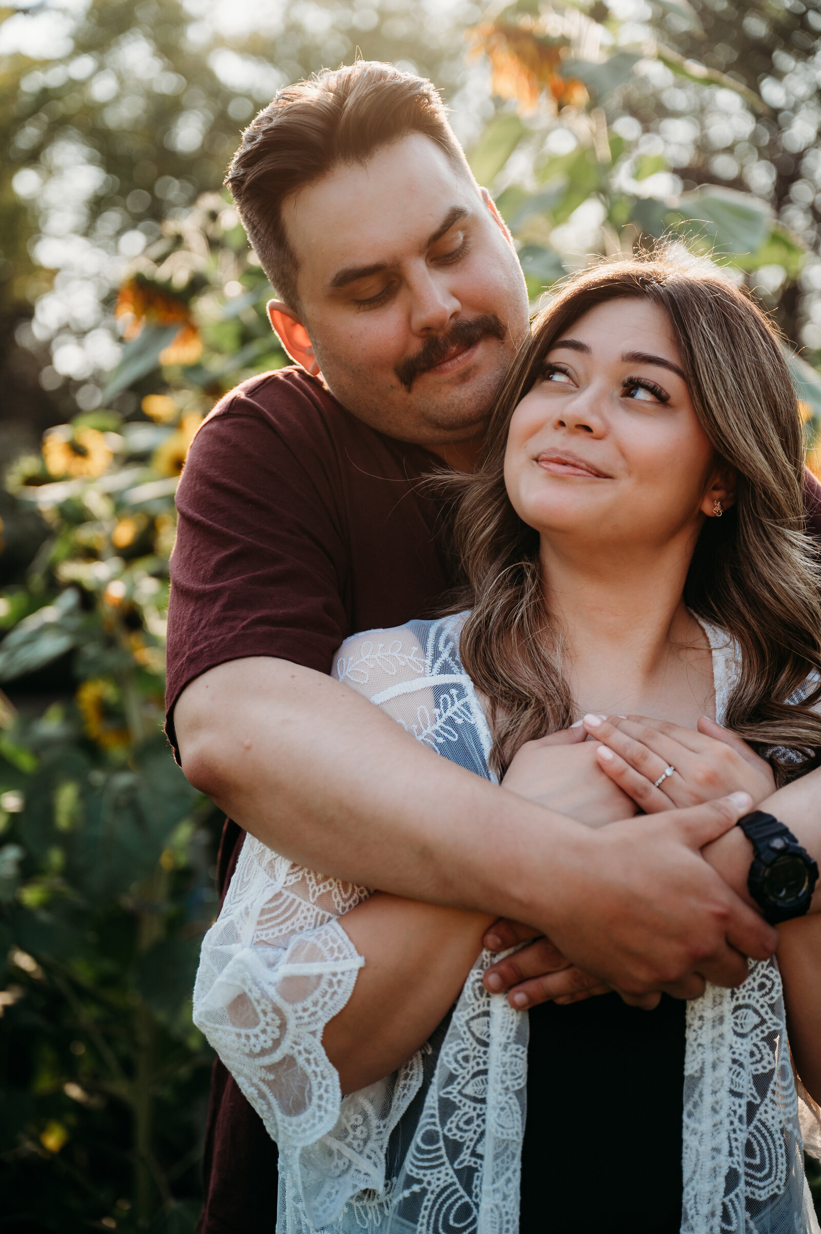 Photo of engaged couple hugging in the flower beds at St.Albert Botanical Gardens