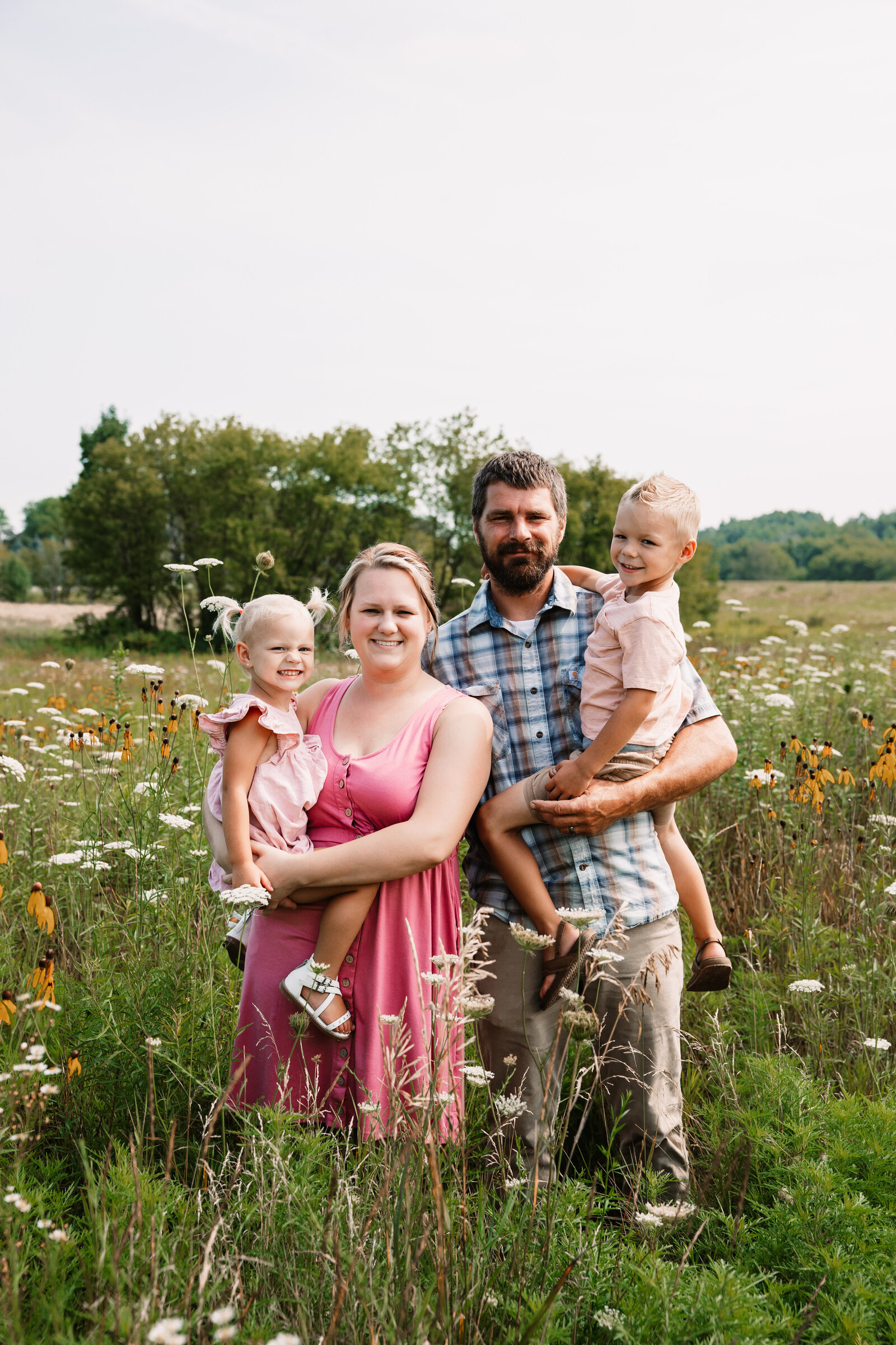 Happy family standing in wildflower field with kids on hips