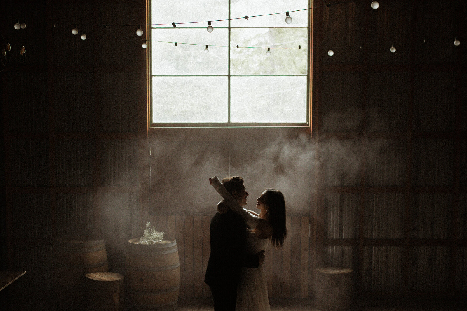 bride and groom dance with fog under festoon lights