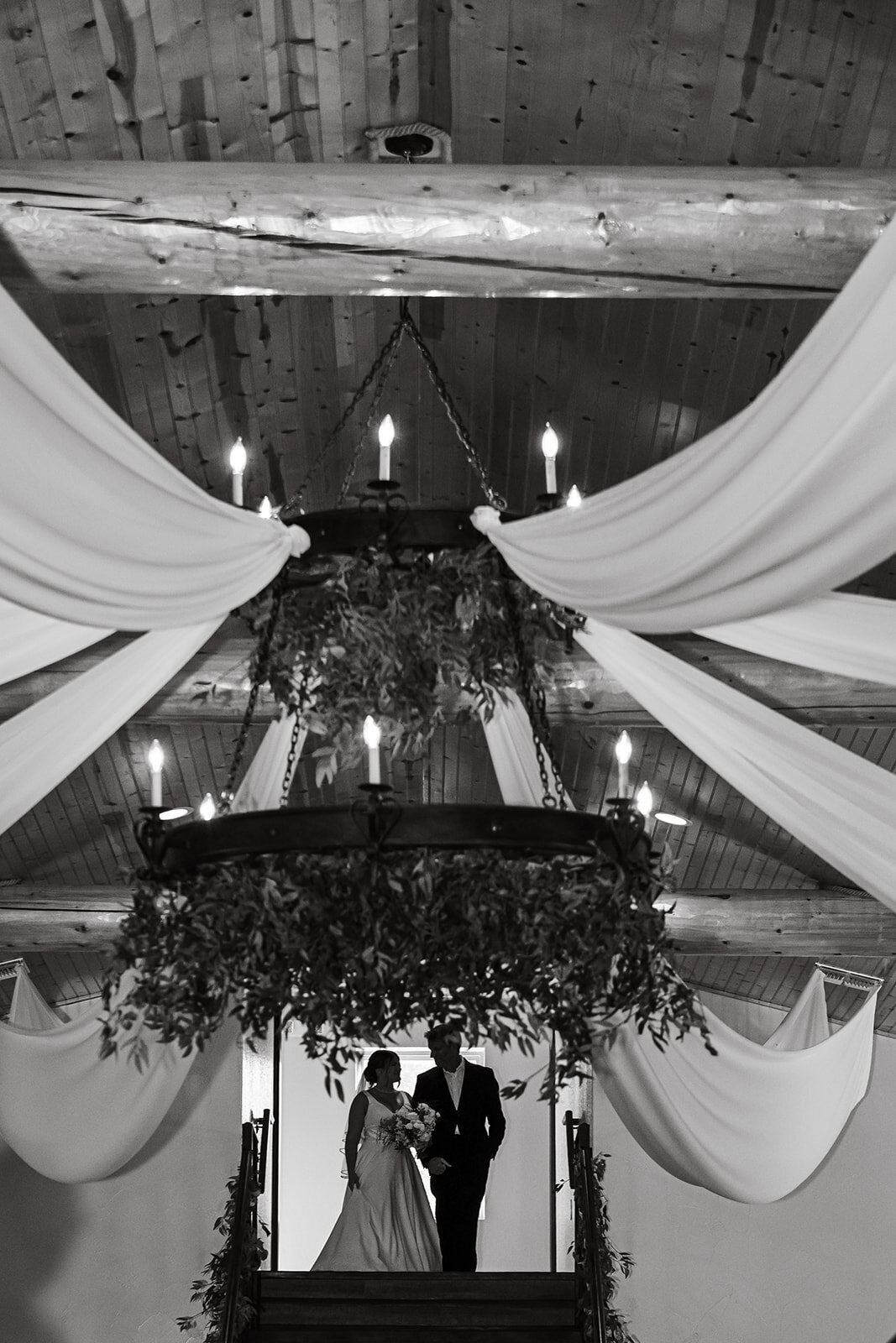 An elegant black-and-white shot capturing the detailed decor and lighting of the wedding ceremony venue, photographed by CMH Studios in San Antonio.