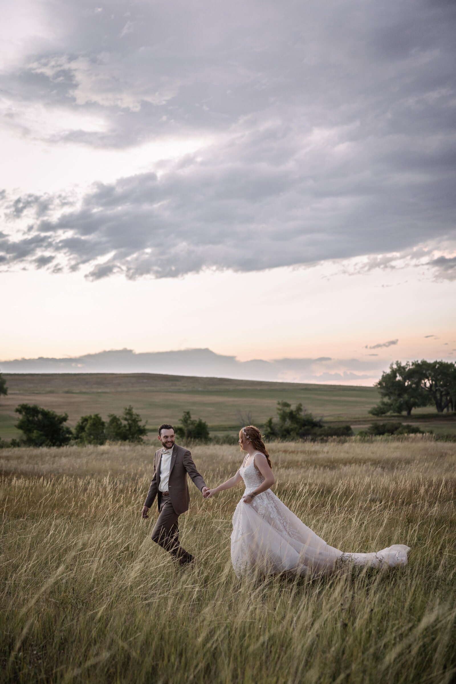 bride and groom walking through field