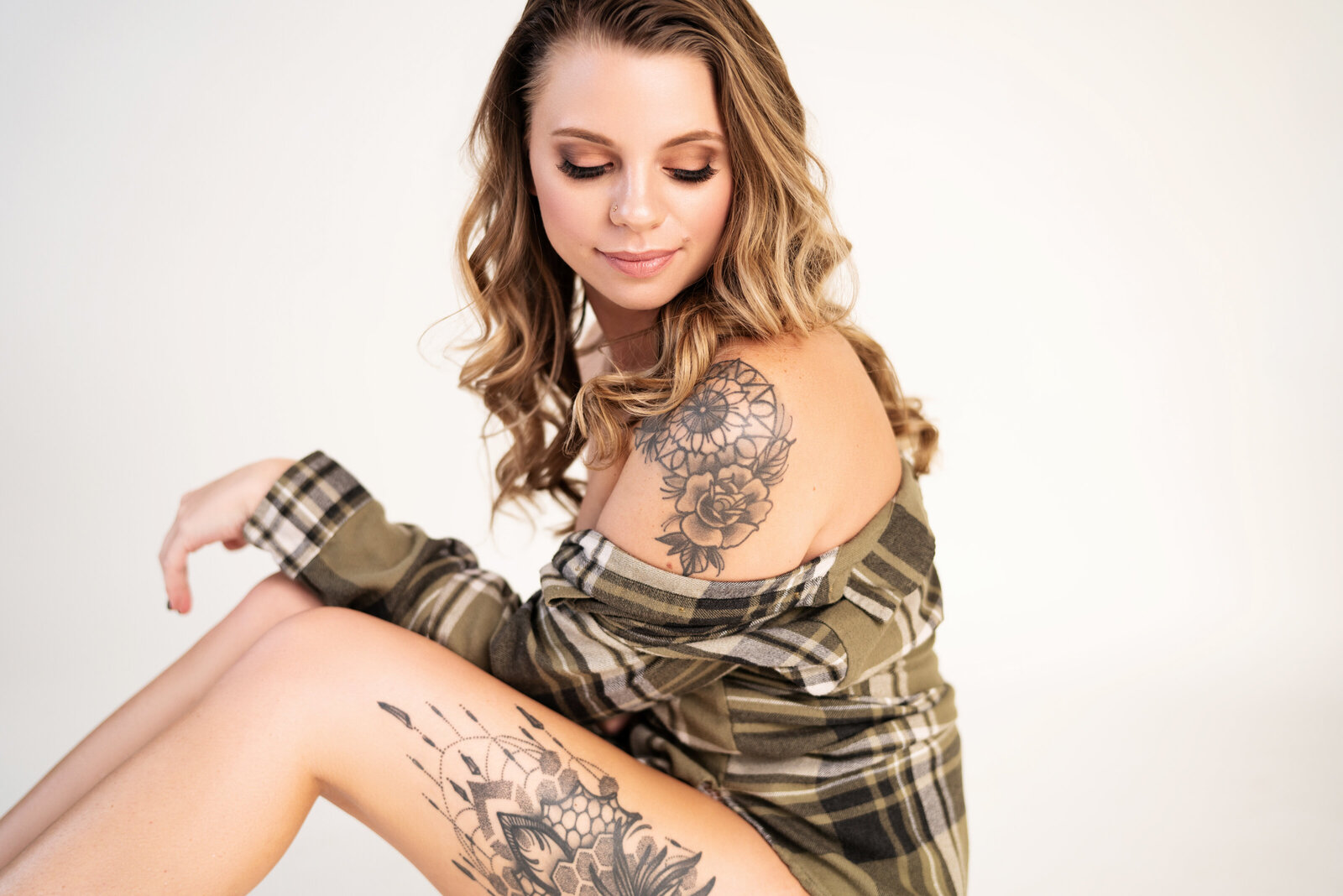 woman sitting on ground in flannel shirt showing tattoos