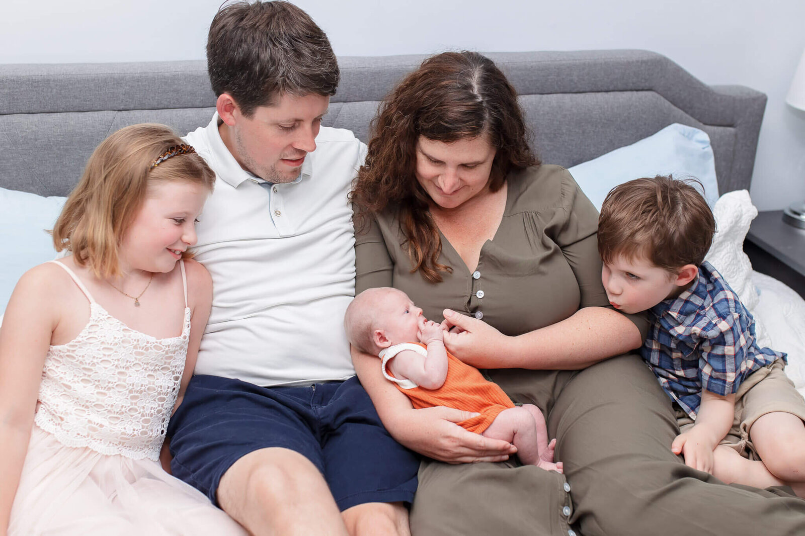 A family of five snuggled in bed during their newborn session.