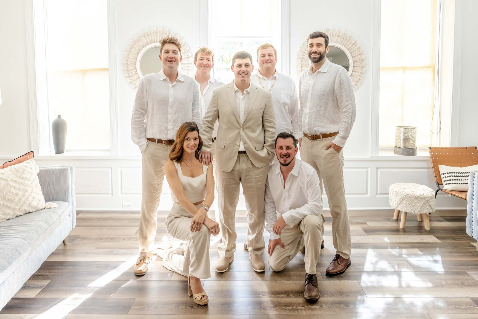 The groom and groomsmen pose in a bright, modern space wearing light beige beach wedding attire, captured during a Topsail Beach, NC wedding, blending casual elegance and coastal charm.