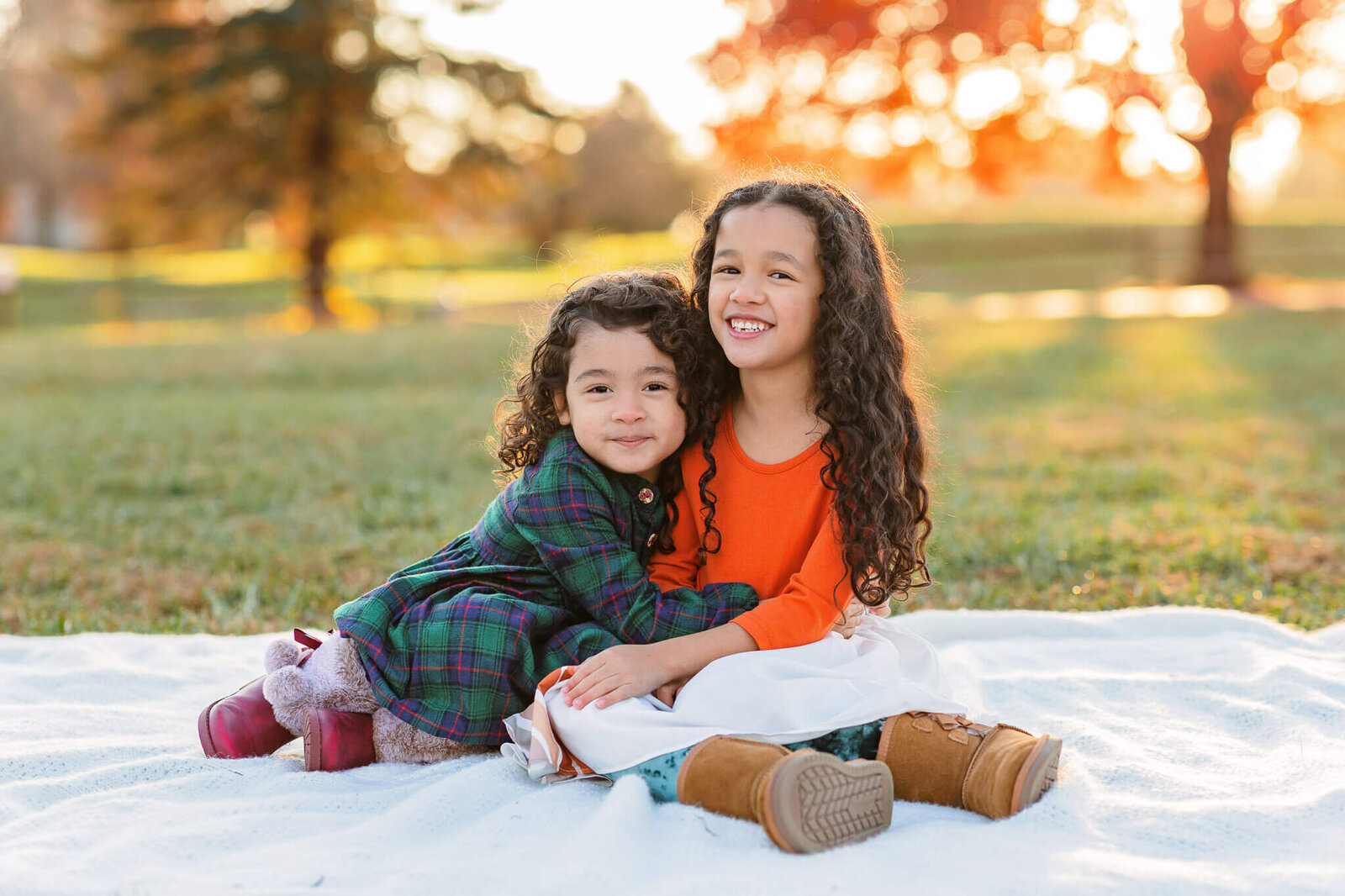 Two sisters sitting on a blanket and hugging