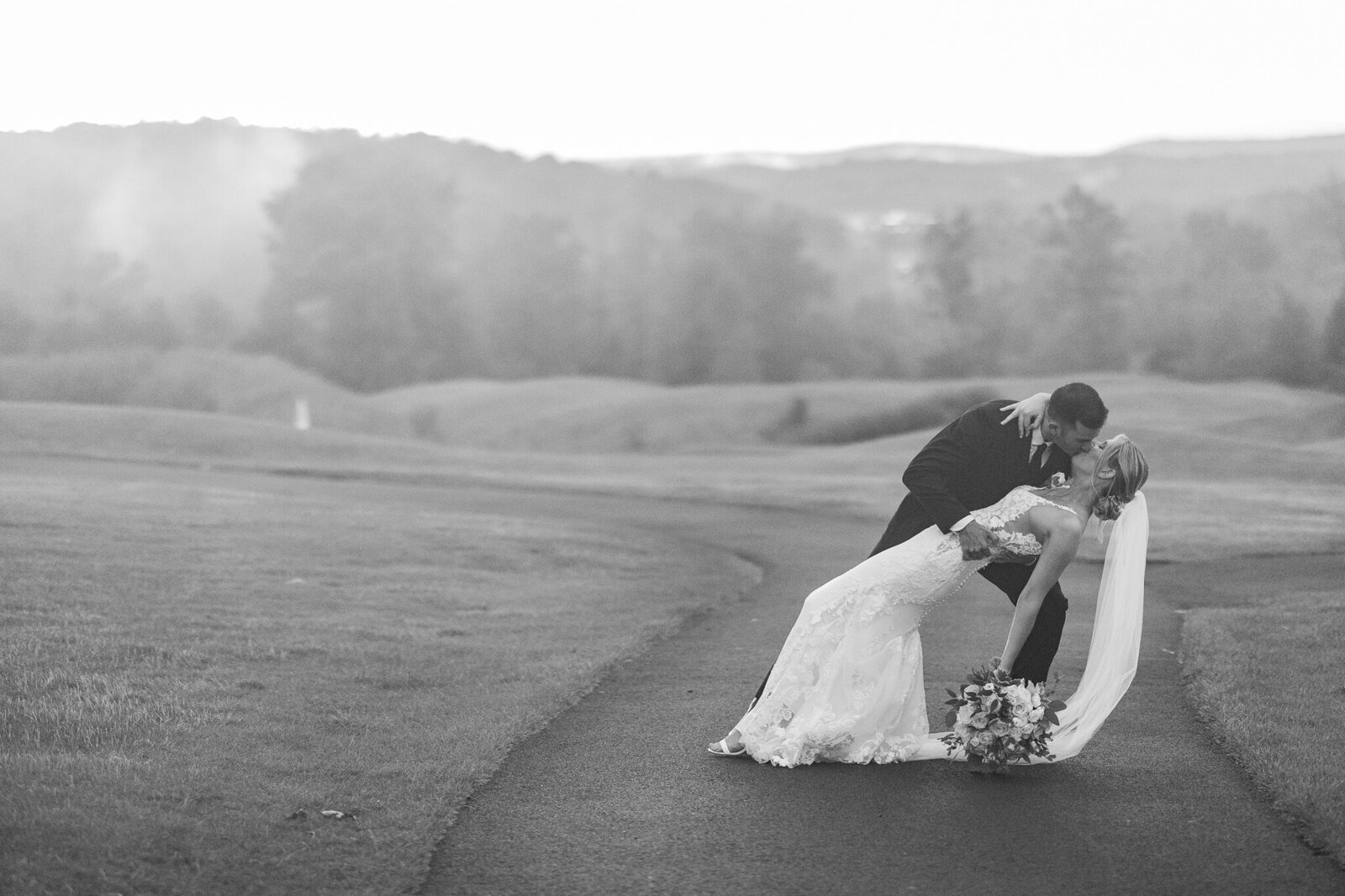 Black and white romantic dip of bride and groom outside in dreamy fog at SkyView Golf Club