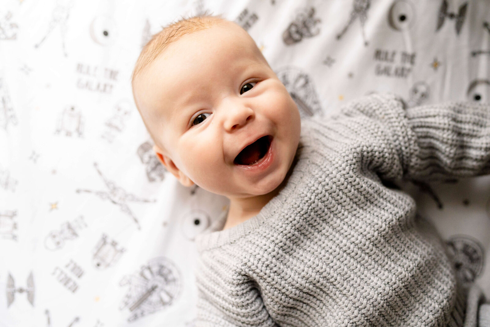 Newborn photographer in Atlanta, Baby in crib smiling at camera