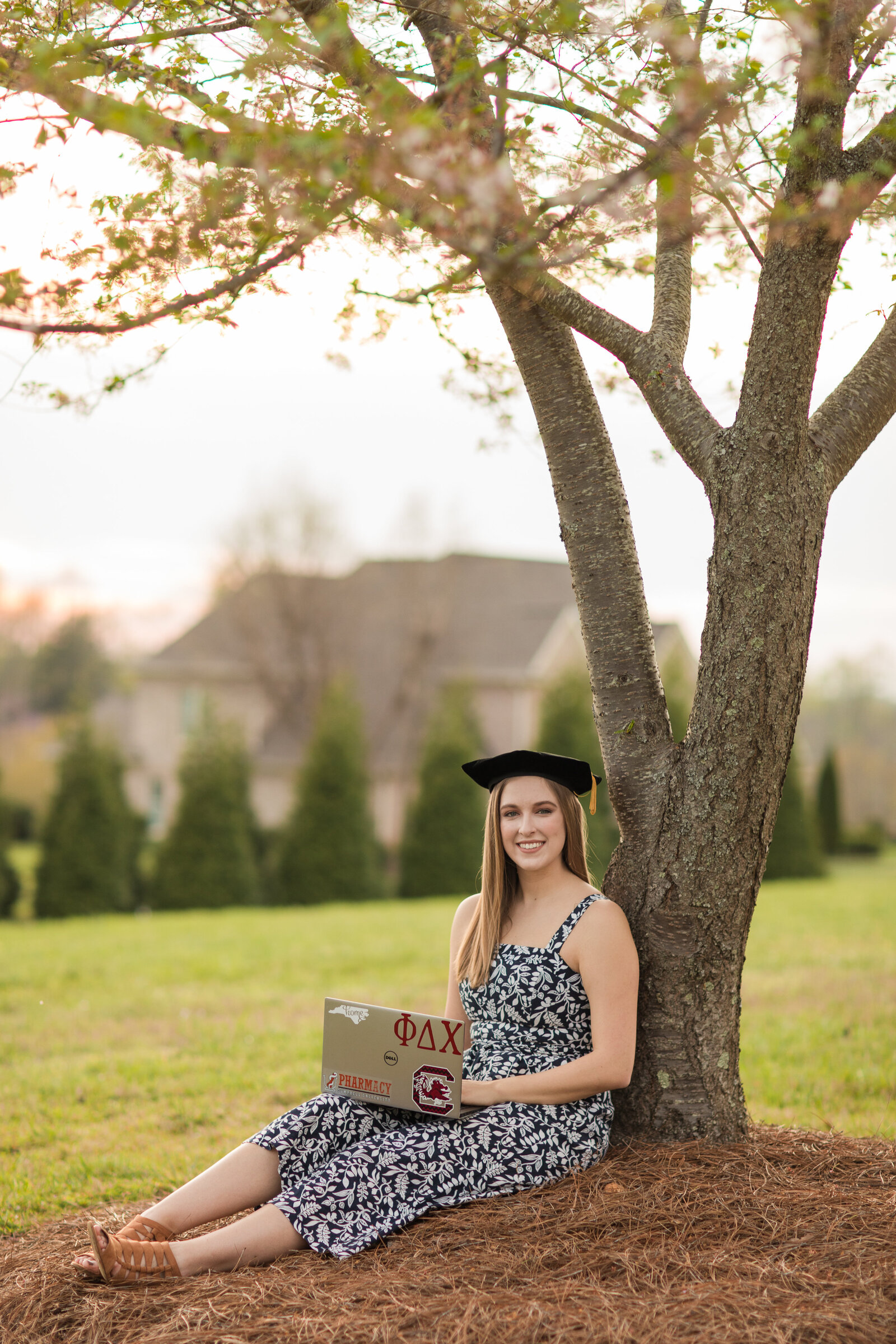 college senior under a tree with laptop