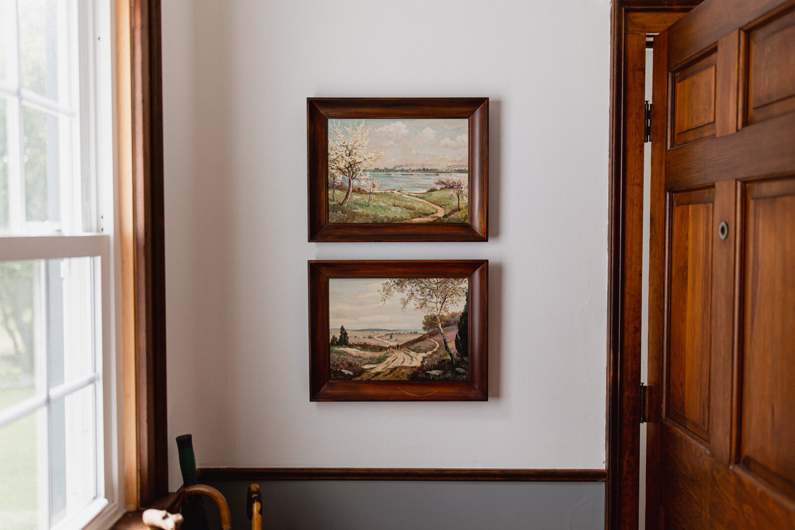 two oil paintings framed in wood  in cottage mud room