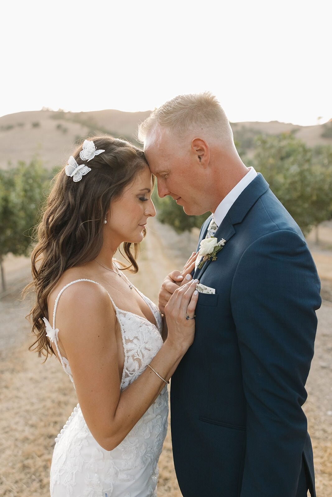 Bride and groom touching foreheads at sunset