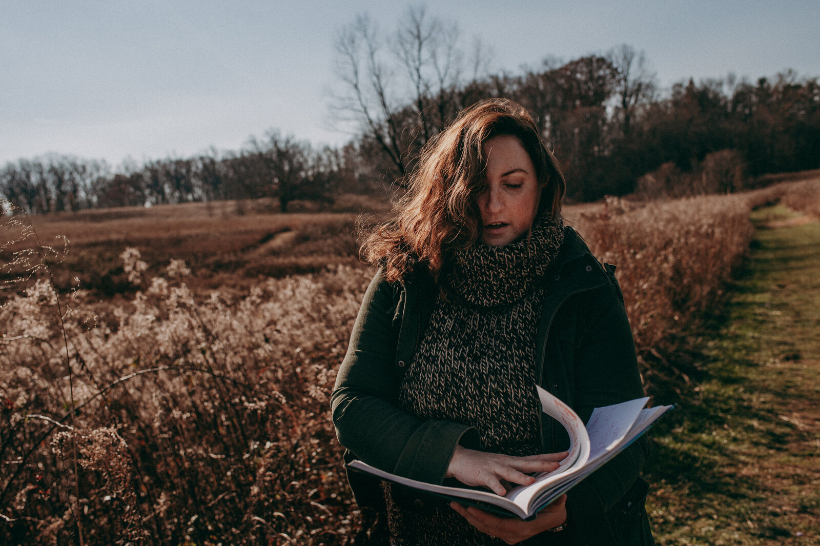 woman in a field looking at sketch book brand photography