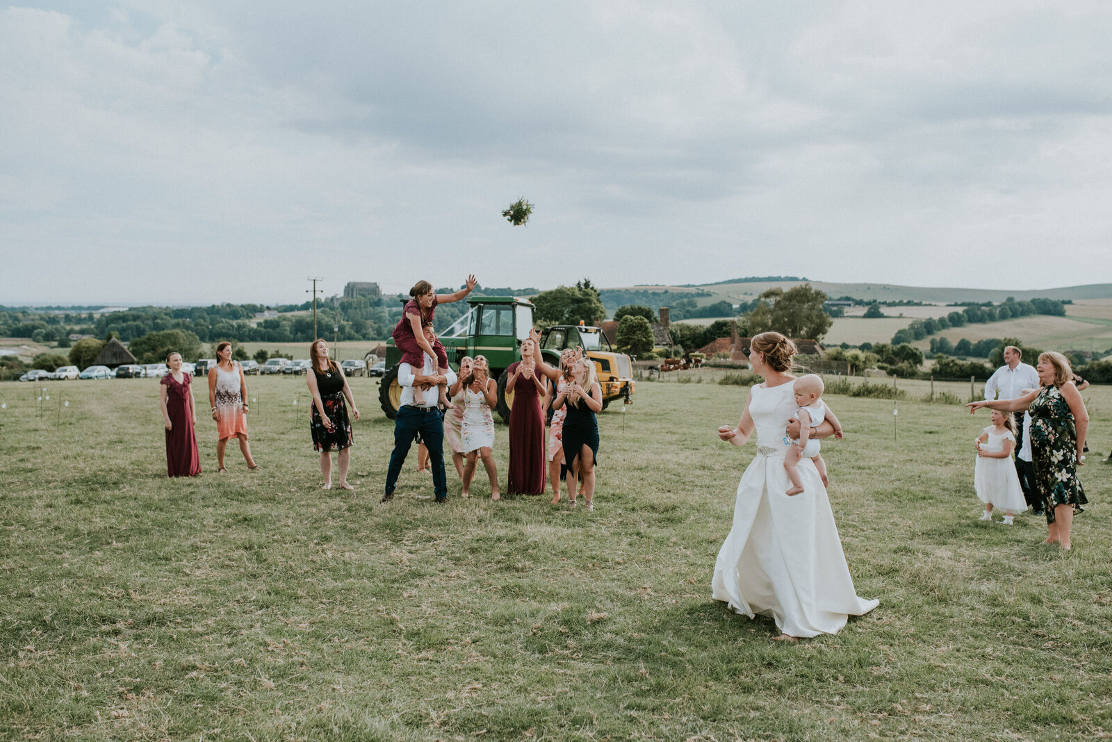 Bride throwing her bouquet to a group of female guests and bridesmaids