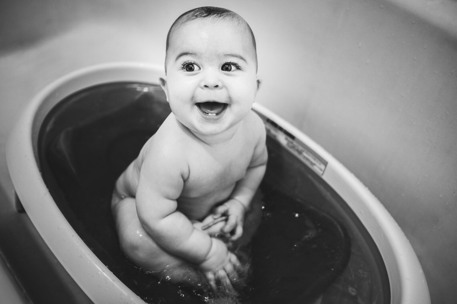 black & white image of happy baby in a bathtub