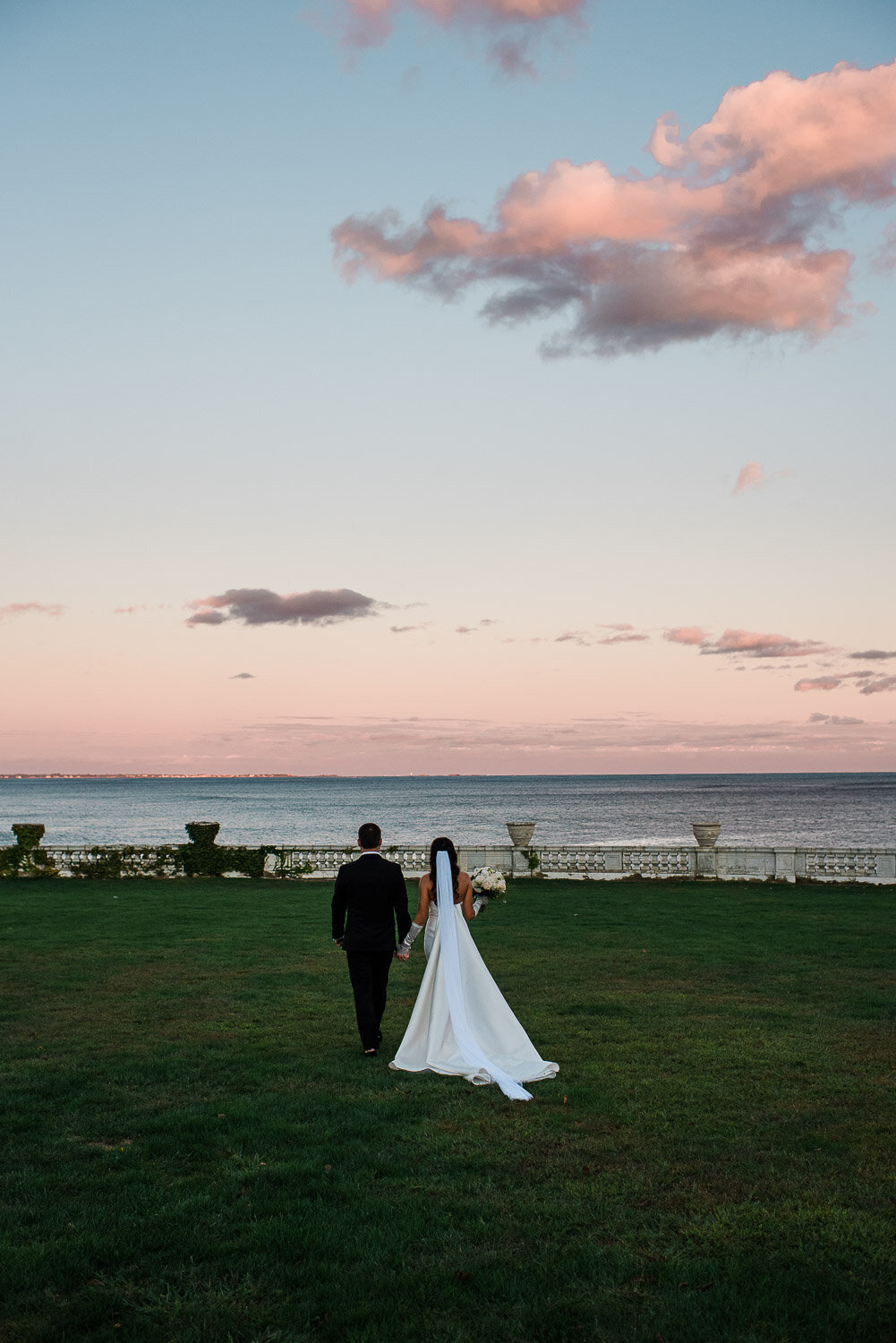 wide of bride and groom from behind walking with cotton candy sky 
