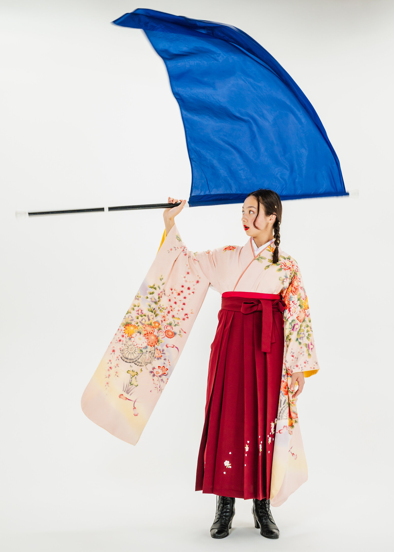 Girl in pink floral kimono and red hakama waving a large blue flag | 卒業式 袴 女の子 ピンク着物 フラッグ演技