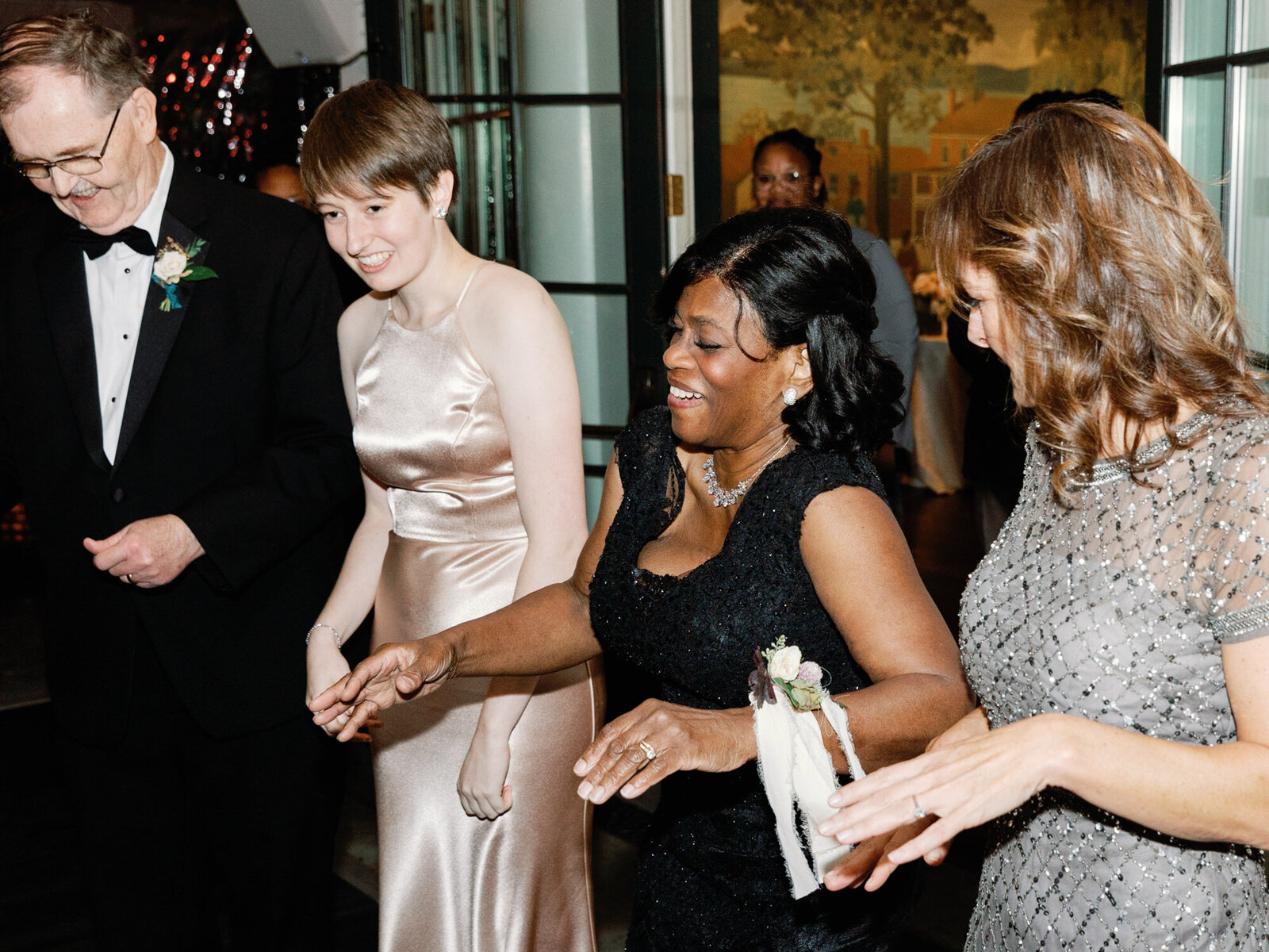 The guests hit the dance floor at a wedding with colorful lights in the background.