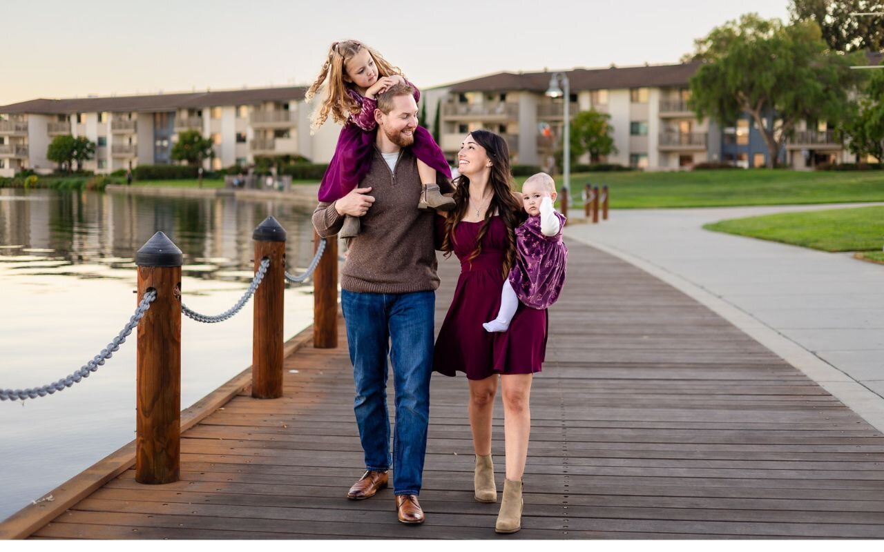 Family walking along the lake boardwalk at sunset in coordinated plum outfits – Ellobelle Photography – Bay Area Family Photographer