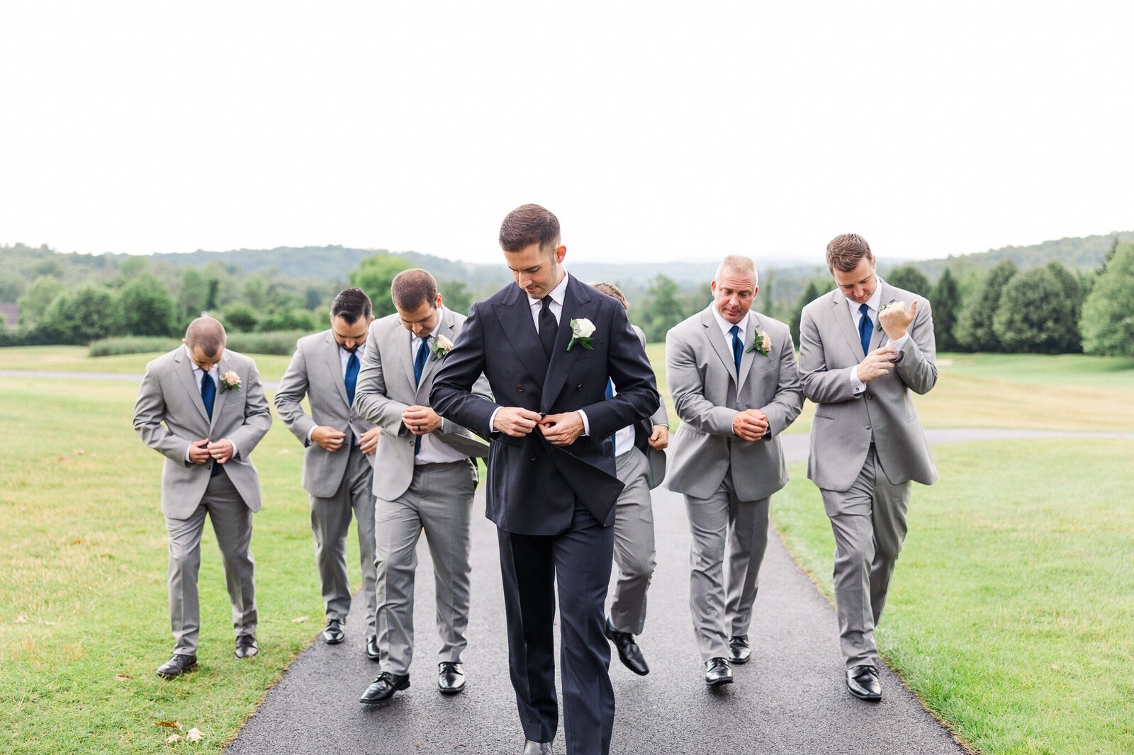 Groomsmen walking and adjusting jackets in motion before ceremony at SkyView Golf Club

