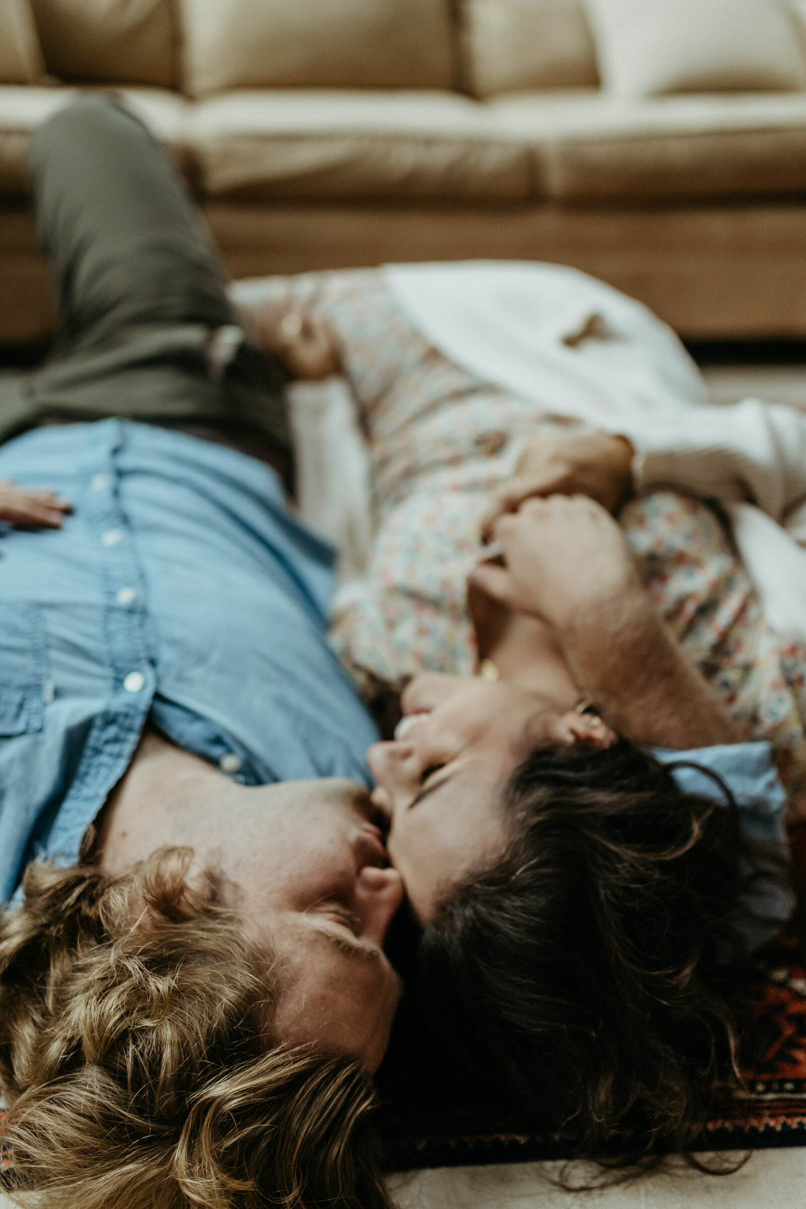 Man and woman lie on the floor and he kisses her forehead