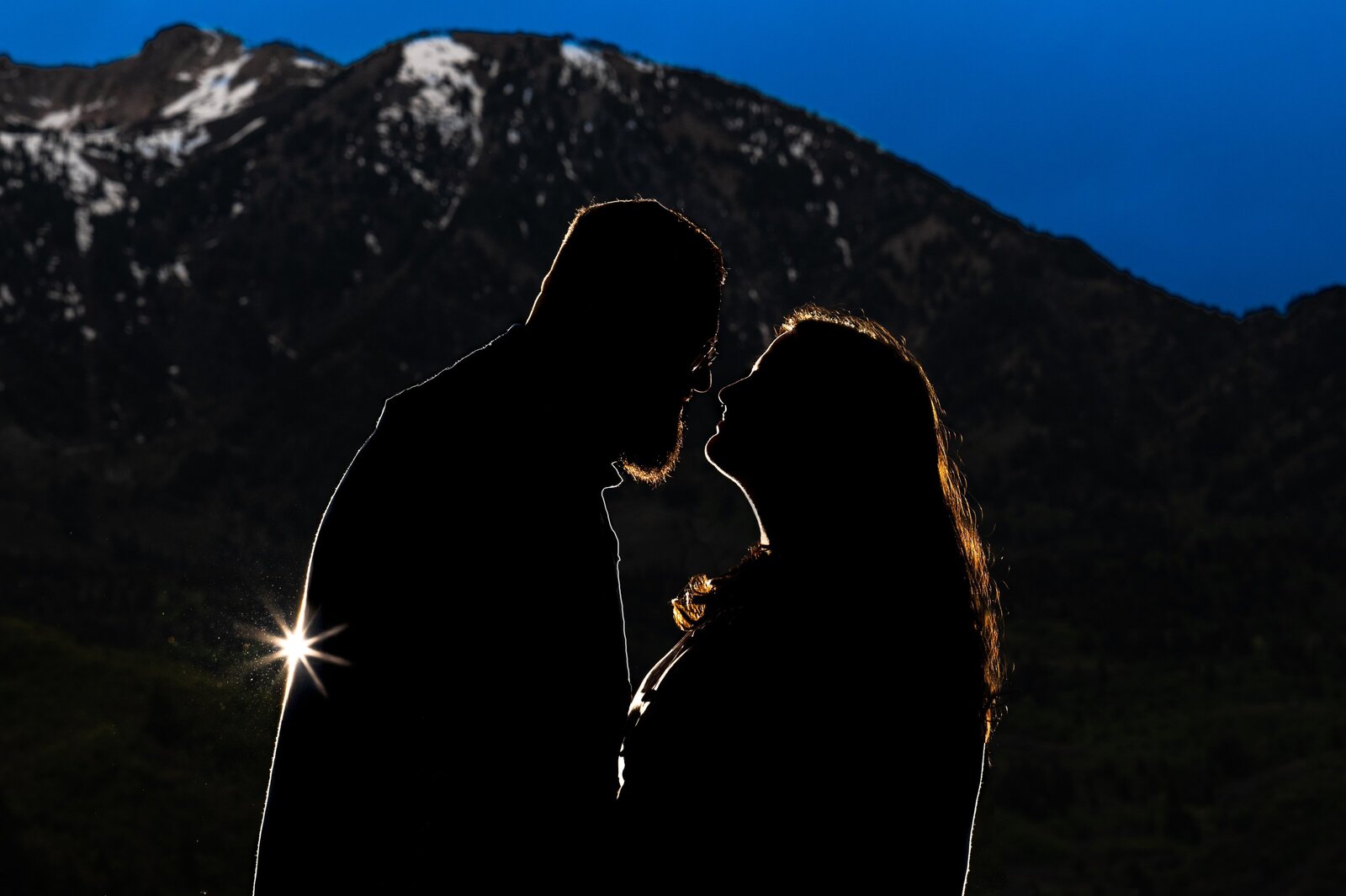 Couple silhouetted with snowy mountain peaks at the backdrop in Utah for their engagement session.